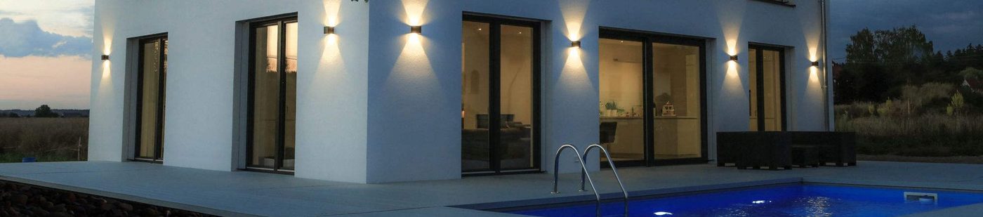 Weißes Wohnhaus, Terrasse mit Pool und Sitzgruppe in der Abenddämmerung
